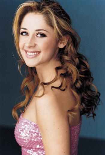 Fotografie ženy s dlouhými vlnitými vlasy a s úsměvem na tváři