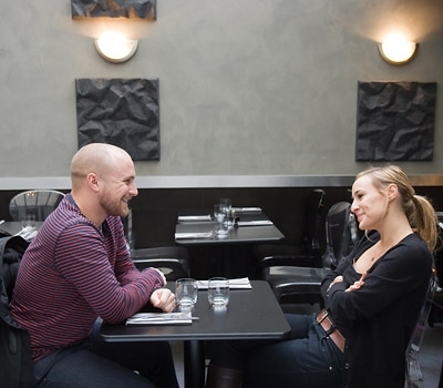 Muž se ženou sedí u stolu se založenými rukami