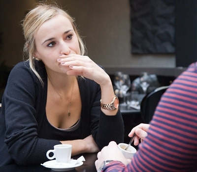 Žena sedící u stolku s rukou před pusou