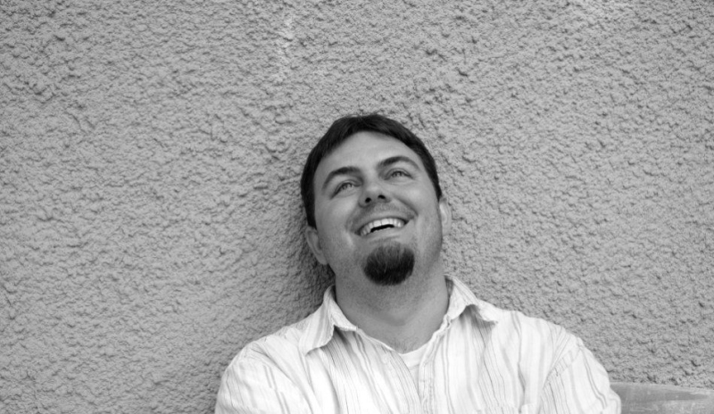 Černobílá fotografie muže, který je opřen o zeď