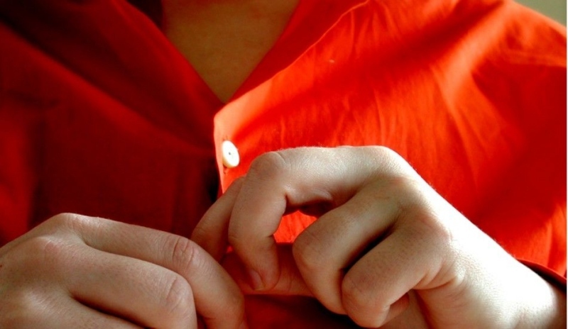 Ruce zapínající knoflíky u košile