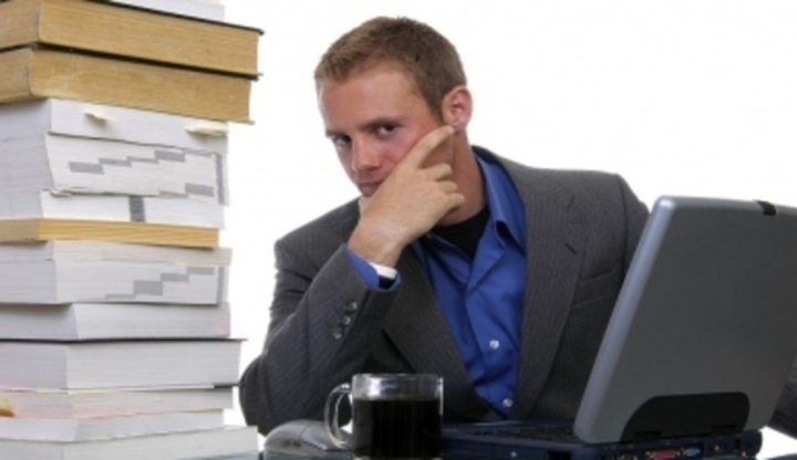 Fotografie muže, který sedí u stolu s počítačem a kopou dokumentů