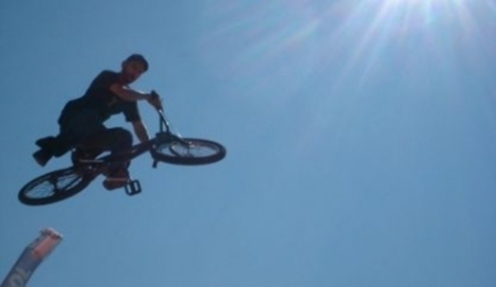 BMX Freestyle – je libo jezdit po předním kole? Záběr letícího závodníka na kole při soutěži BMX