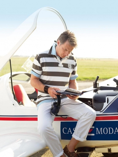 Snímek muže v proužkovaném triku sedící na stole