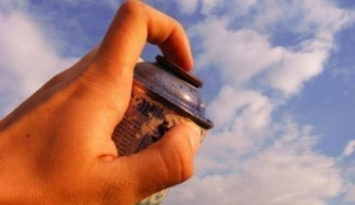 Detailní záběr na mužskou ruku při sprejování na nebe