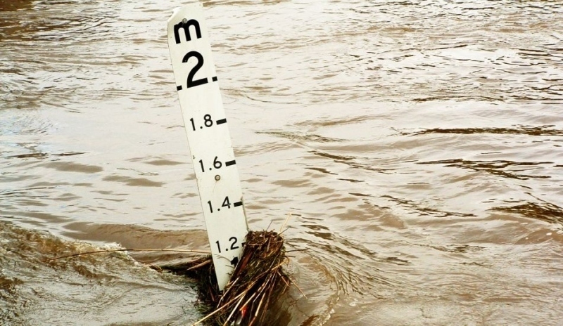 Fotografie zobrazující povodeň a zatopený ukazatel