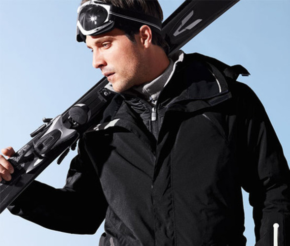 Fotografie zachycující muže v černém lyžařském oblečení s lyžemi