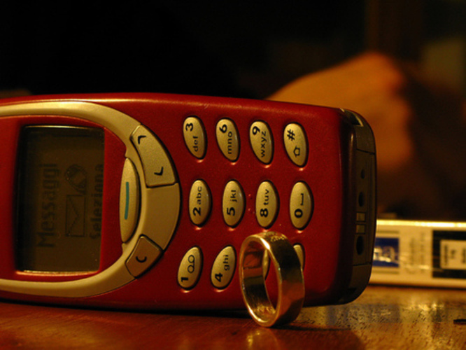 Mobilní telefon a krabička cigaret ležící na stole
