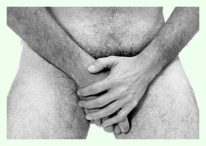 Jak cvičit, abych ho měl většího? Černobílá fotografie muže, který si chrání odhalený rozkrok