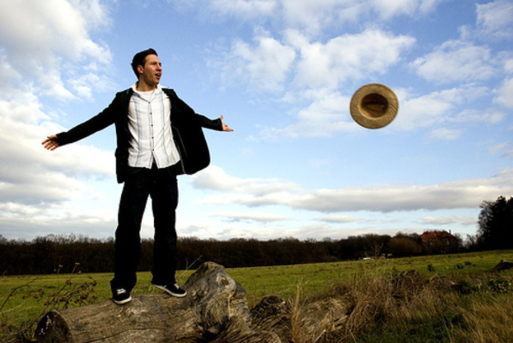 Fotografie muže, který v poli odhazuje svůj klobouk