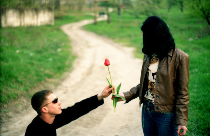 Džentlmeni jsou in – čím ji okouzlíte? Muž poklekl před ženou s kytkou v ruce, jenž ženě věnuje