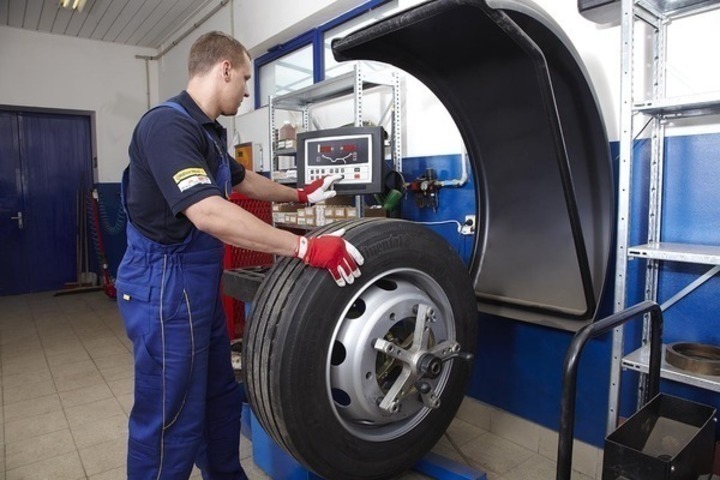 Kde si nechat opravit pneumatiky? Fotografie muže při práci s pneumatikou