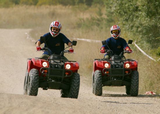 Fotografie dvou osob jedoucí na čtyřkolkách