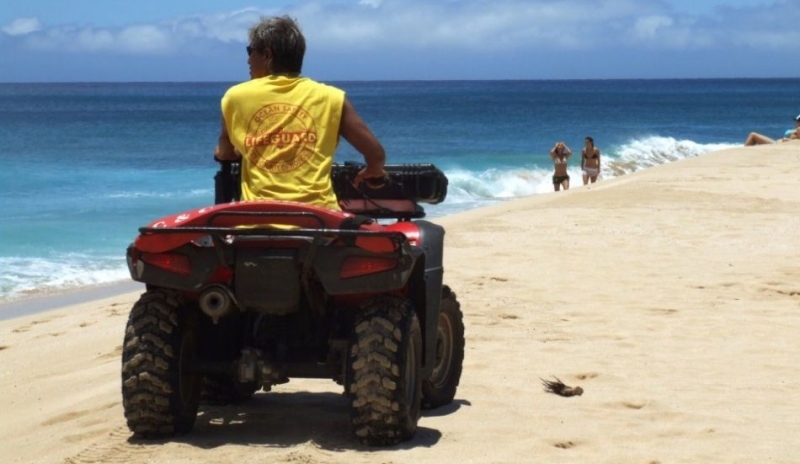 Fotografie plavčíka na čtyřkolce jedoucí po pláži