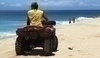 Fotografie plavčíka na čtyřkolce jedoucí po pláži