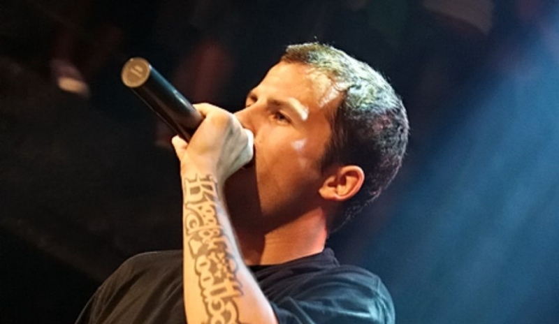 Muž s tetováním na ruce a s mikrofonem