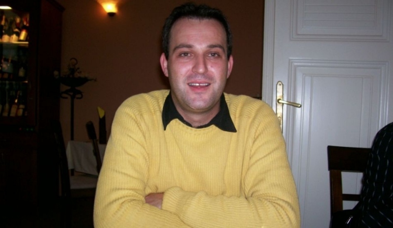 Muž ve žlutém svetru se založenými rukami