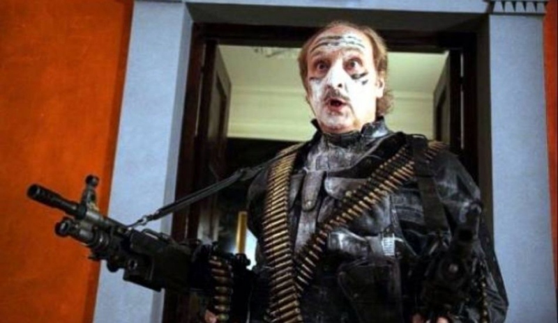 Fotografie muže se zbraní v ruce a s dvěma pásy nábojů na těle