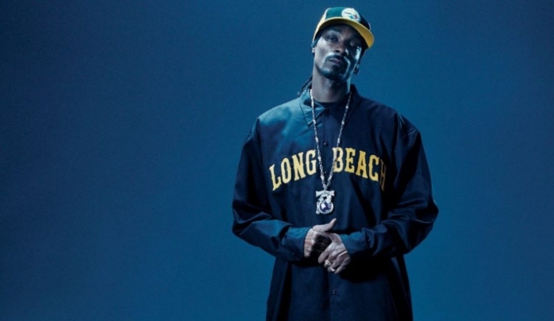 Muž v dlouhé modré košili s kšiltem na hlavě