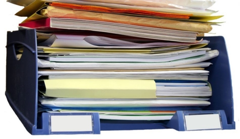Fotografie zobrazující hromadu tiskopisů v pořadači