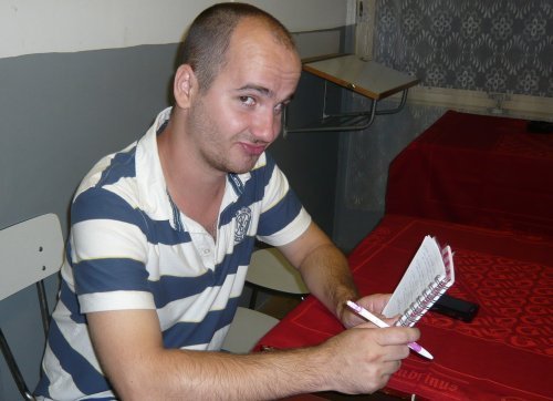 Muž v pruhovaném triku s blokem a tužkou v ruce