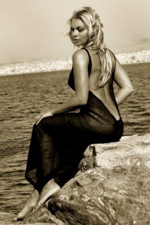 Lucie Borhyová sedí v černých šatech u moře