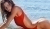Fotografie ženy v červených plavkách ležící na břehu moře