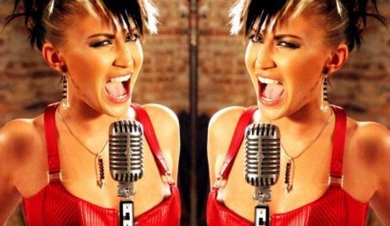 Gábina Partyšová stojící u mikrofonu a sexy červených šatech