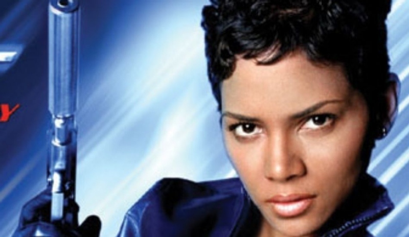 Halle Berry v modré kožené bundě s pistolí v ruce