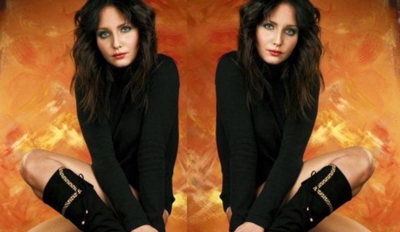 Veronika Nová v černém svetru a černých kozačkách na oranžovém podkladu