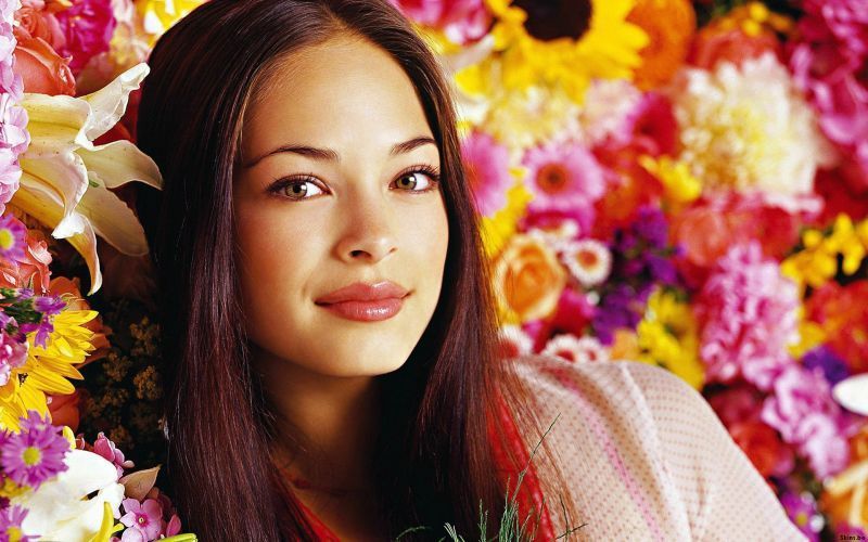 Půvabná herečka Kristin Kreuk s barevnými květy v pozadí