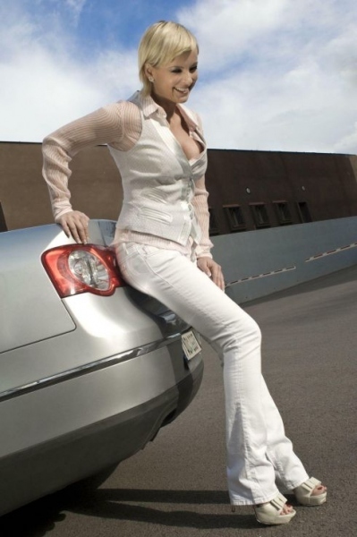 Iveta Bartošová v bílém kostýmu se opírá o auto