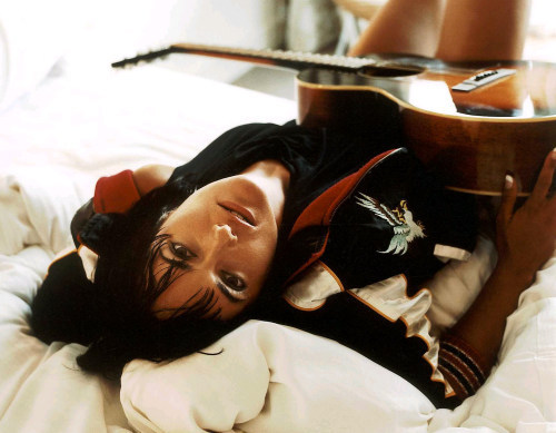 Sian Evans leží s kytarou na posteli