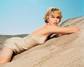 Charlize Theron ležící na písku