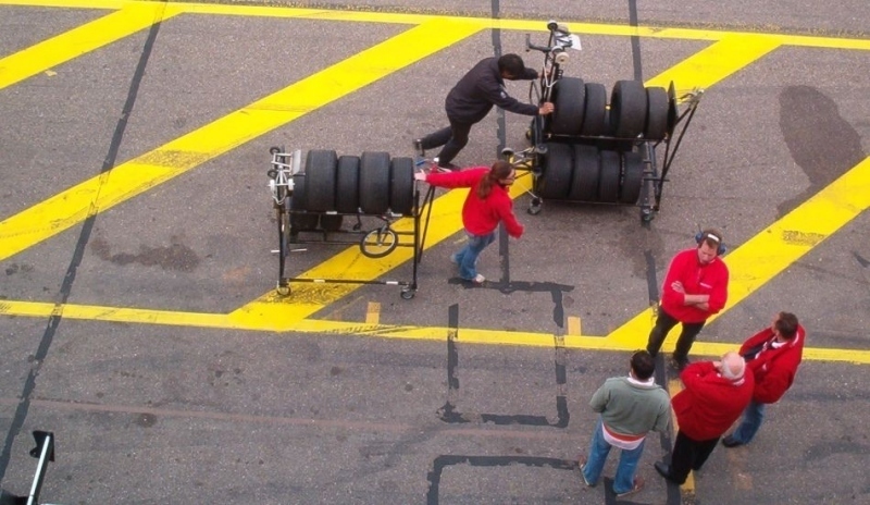 Snímek zobrazující postavy tlačící pneumatiky na stojanu.