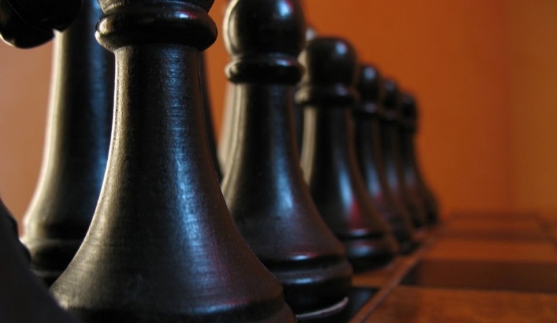 Snímek černých figurek na šachovnici