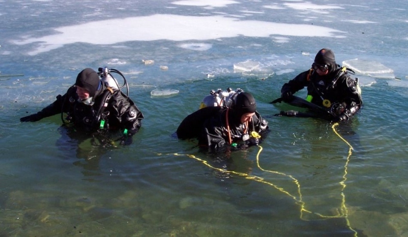 Fotografie tří potápěčů vycházejících z vody