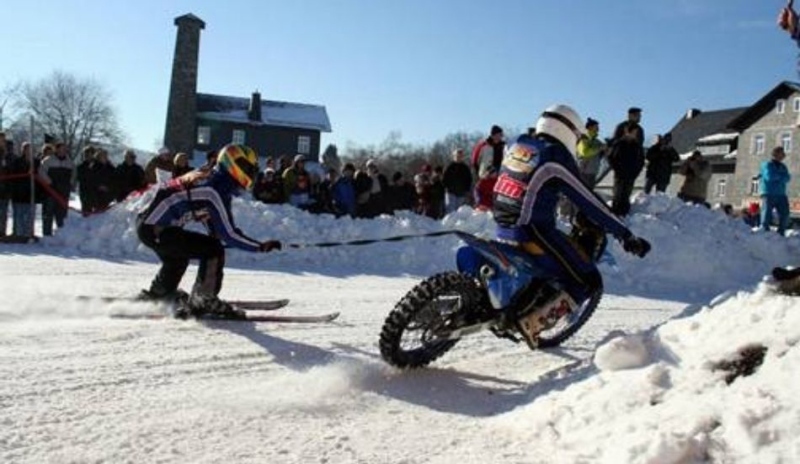 Snímek řidiče na motorce vezoucího za sebou lyžaře na laně