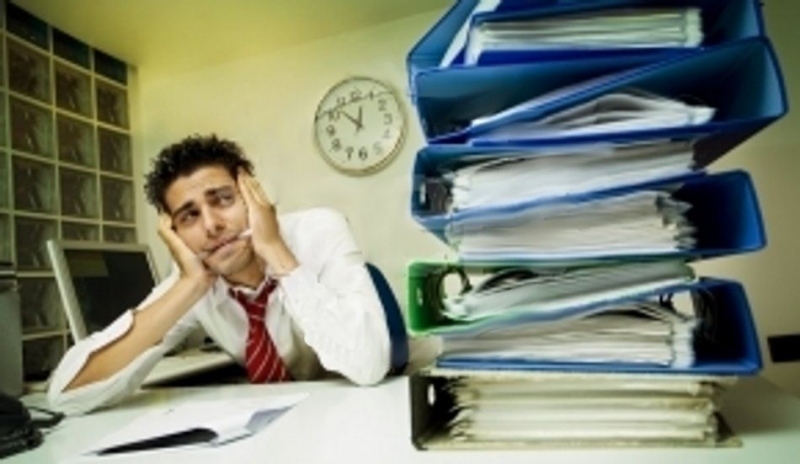 Muž sedící za stolem plném papírů v šanonech