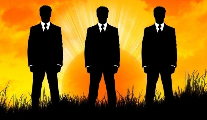 Siluety tří mužů ve sluneční záři