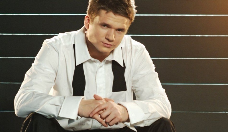 Ondřej Brzobohatý v bílé košili a černých kalhotech sedící na schodech