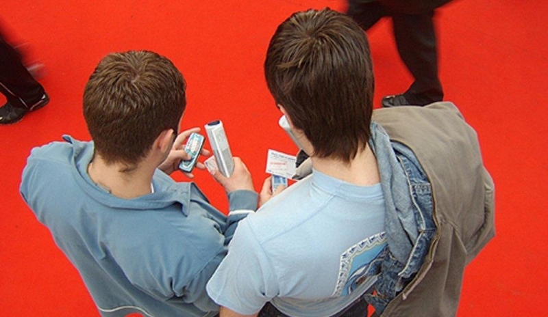 Snímek zobrazující dva muže s telefonem v ruce