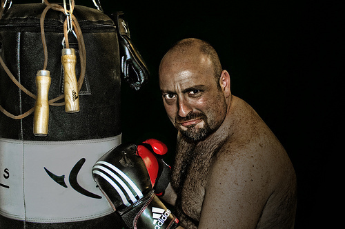 Muž v boxerských rukavicích stojící u boxerského pytle