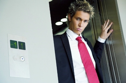 Muž v saku, bílé košili a růžové kravatě s podmanivým pohledem