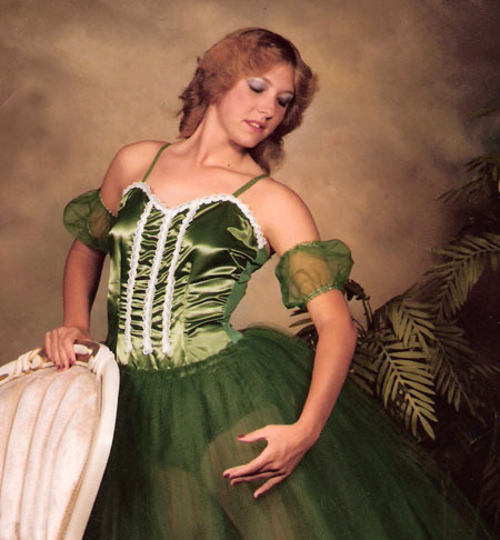 Fotografie ženy v zelených šatech opírající se o židli