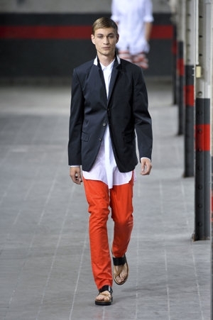 Muž v oranžových kalhotech, bílé košili a modrém saku