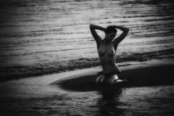 Obrázek nahé ženy sedící na pláži