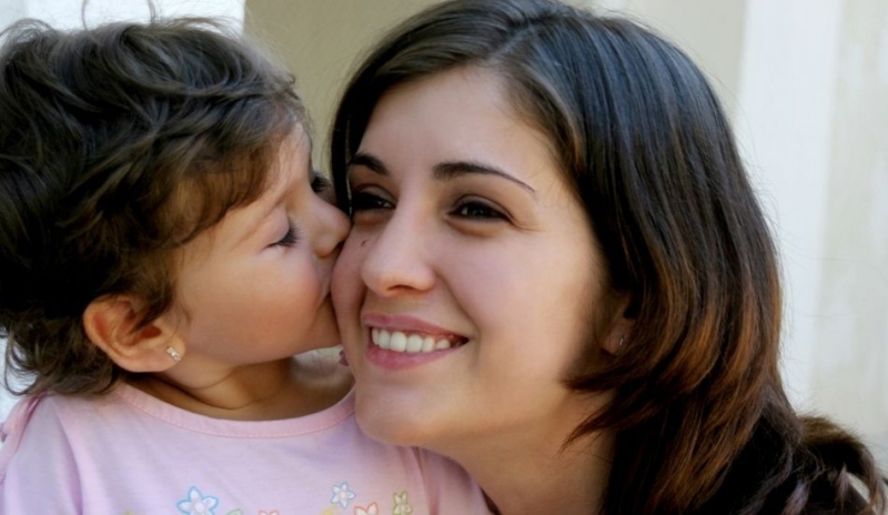 Dítě líbající ženu na tvář