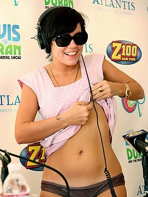 Bruneta ve slunečních brýlích s vyhrnutým trikem odhaluje břicho